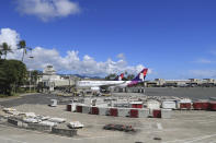 An airplane is seen parked at a terminal at the the Daniel K. Inouye International Airport Thursday, Oct. 15, 2020, in Honolulu. A new pre-travel testing program will allow visitors who test negative for COVID-19 to come to Hawaii and avoid two weeks of mandatory quarantine goes into effect Thursday. The pandemic has caused a devastating downturn on Hawaii's tourism-based economy. Coronavirus weary residents and struggling business owners in Hawaii will be watching closely as tourists begin to return to the islands. (AP Photo/Marco Garcia)