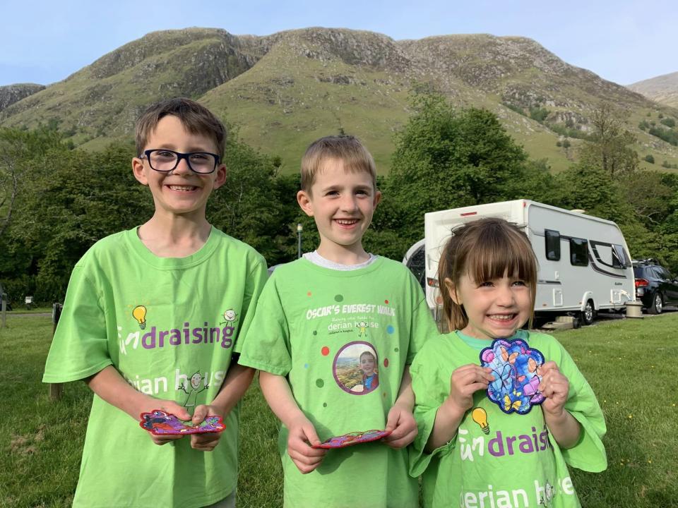 Three children wearing green t-shirts and smiling at the camera