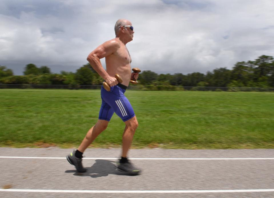 Mike Lynch runs 50 yards carrying dumbbells recently at the track at Pine View School in Osprey, Florida.