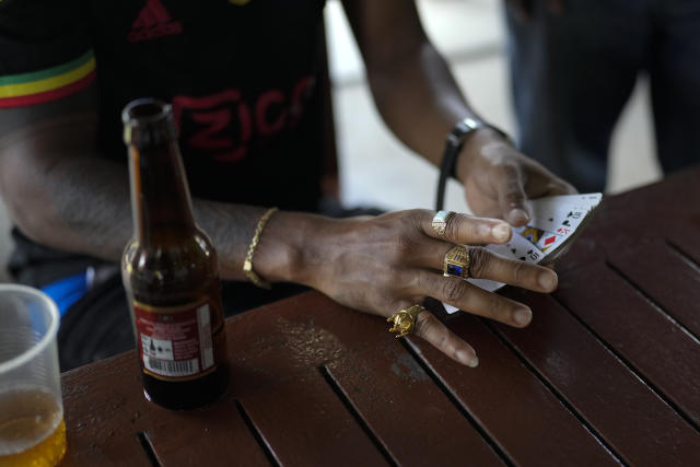 Oil workers play cards outside the Ogle International Airport in Georgetown, Guyana, Friday, April 14, 2023. The Ogle airport is a gathering place for oil workers who are air lifted by helicopter from sea rigs, where they live and work for a month. (AP Photo/Matias Delacroix)