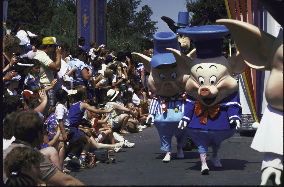 Cast members parade past the crowd at Disney World.