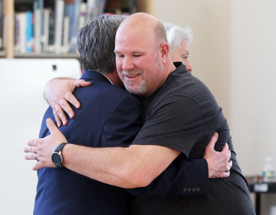 Steve Pappajohn, the Youth Services Coordinator for Dover Police Department and steering member of Dover Mental Health Alliance, hugs Judge John Broderick, former NH Supreme Court Chief Justice, during an opening reception of the Mental Health: 99 Faces Project.