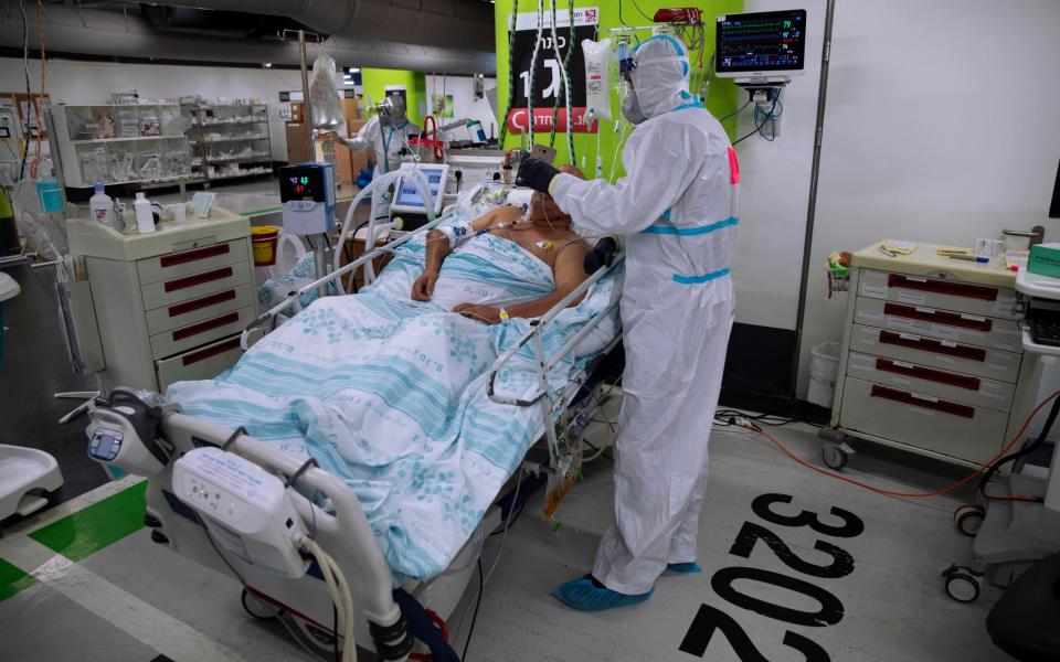 A medical worker wearing protective equipment treats a COVID-19 patient in an intensive care ward - AP/Oded Balilty 