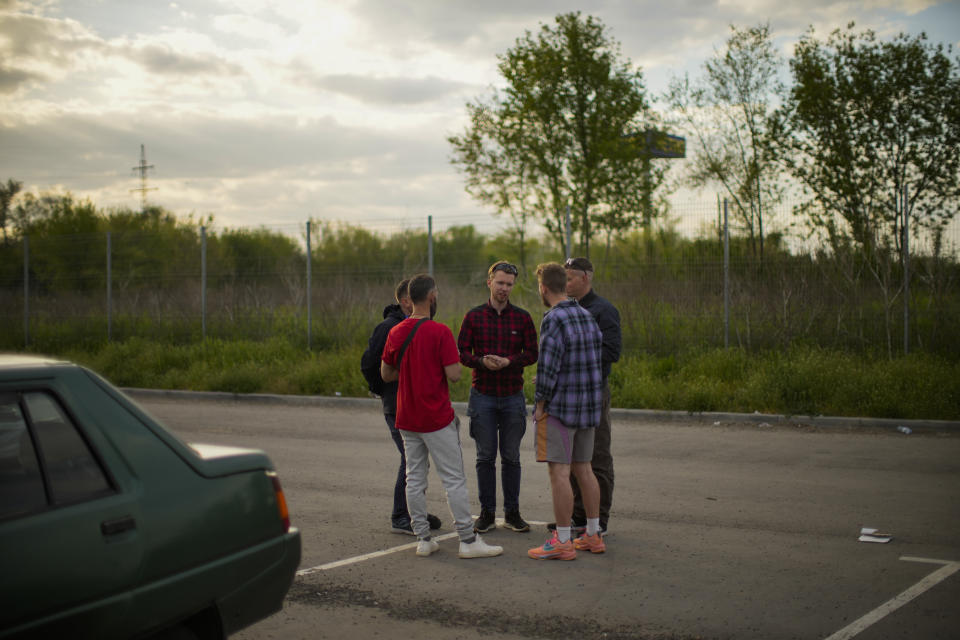 Oleksandr Petrenko, center, speaks with other volunteers in a reception center for displaced people in Zaporizhzhia, Ukraine, Tuesday, May 10, 2022. Volunteer drivers are risking everything to deliver humanitarian aid to Ukrainians behind the front lines of the war — and to help many of them escape. The routes are dangerous and long and the drivers risk detention, injury or death. (AP Photo/Francisco Seco)