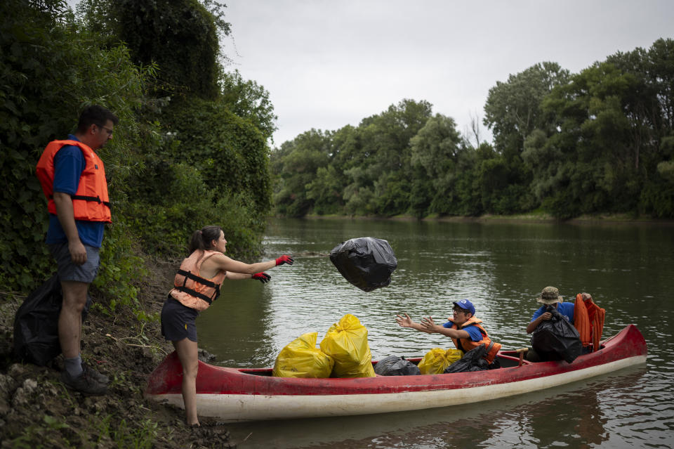 Volunteers collect rubbish from the banks of Tisza river near Tiszaroff, Hungary, Tuesday, Aug. 1, 2023. Life-jacketed rivergoers of all ages pile into dozens of canoes to scour Hungary’s second-largest river for trash that has flowed downstream. (AP Photo/Denes Erdos)