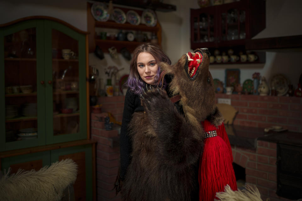 Maria, 22 years-old, a member of the Sipoteni bear pack, poses for a portrait in Comanesti, northern Romania, Wednesday, Dec. 27, 2023. Maria first wore the bear fur costume when she was 5 years old and feels a connection to her departed father who introduced her to the tradition 17 years ago, shortly before his death. She feels the bear dance chases the bad spirits away and liberates her soul. (AP Photo/Andreea Alexandru)