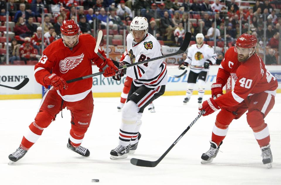 Detroit Red Wings defenseman Brian Lashoff (23) battles with Chicago Blackhawks right wing Marian Hossa (81), of the Czech Republic, and Henrik Zetterberg (40), of Sweden, in the first period of an NHL hockey game Wednesday, Jan. 22, 2014, in Detroit. (AP Photo/Paul Sancya)