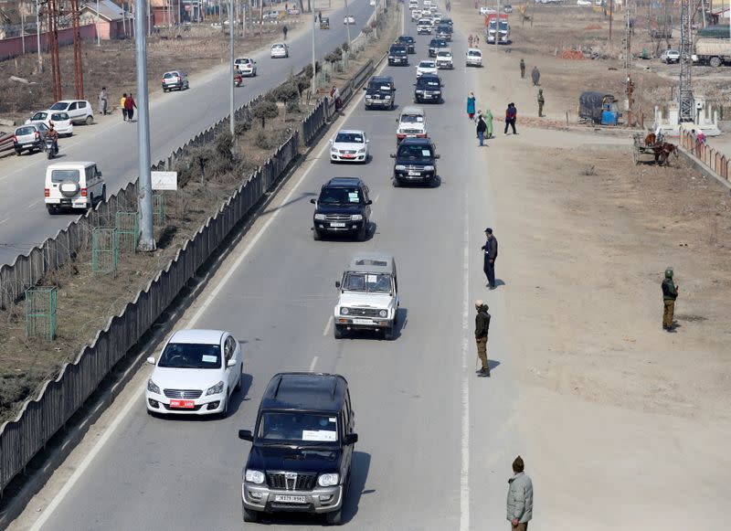 Indian policemen stand guard as a convoy carrying foreign diplomats moves on a road in Srinagar