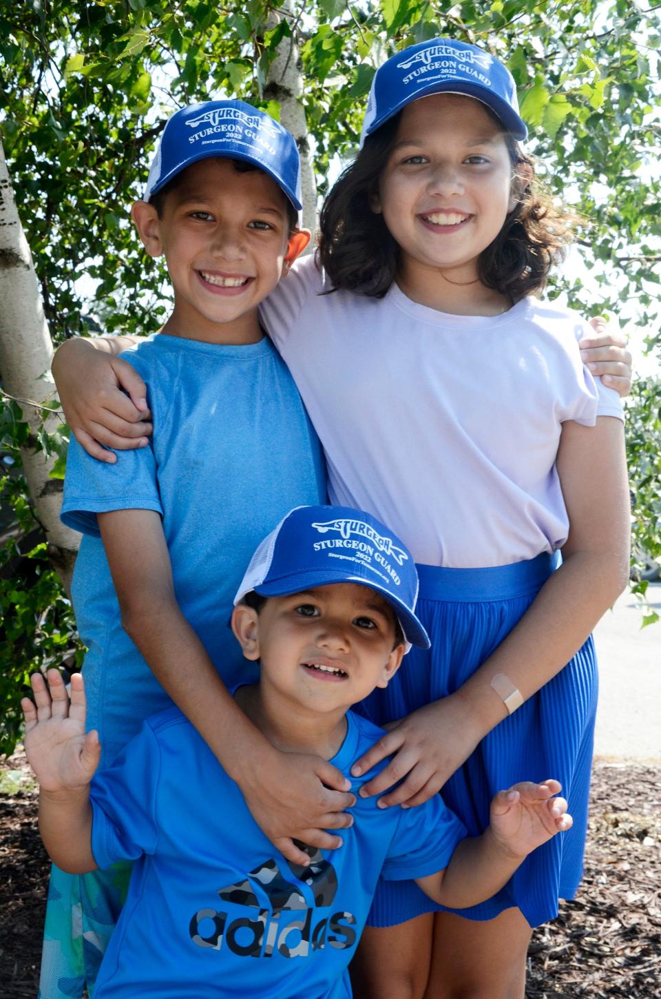 Gabriella, Santiago and Mateo Morado, of Harbor Springs, show off their new Sturgeon Guard hats from the Sturgeon for Tomorrow booth on Thursday, Aug. 3, 2023 during an open house at the Oden State Fish Hatchery.