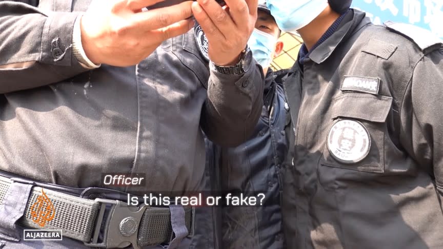 一群警察圍住 Yang Jun，要求他拿出證件，警方拿到證件後仍狐疑 Yang Jun 記者身分的真實性。（圖片來源／截自 Aljazeera YouTube 影片）
