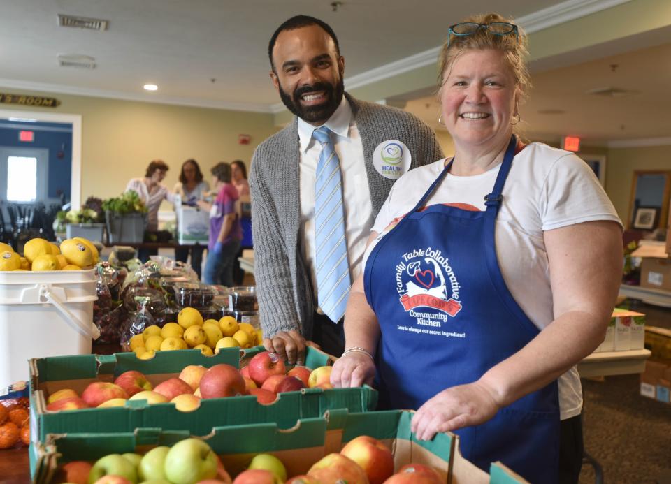 Mike Mecenas, with the Health Ministry Inc. in Hyannis, and Jeni Wheeler are surrounded by fruits and vegetables at the Family Table Collaborative's distribution area in South Yarmouth, where volunteers box up fresh produce.