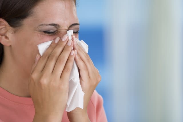 Woman blowing nose into tissue