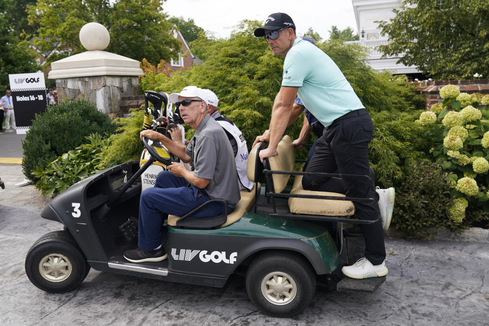 Henrik Stenson, of Sweden, right, rides to the 10th tee during the final round of the Bedminster Invitational LIV Golf tournament in Bedminster, N.J., Sunday, July 31, 2022. (AP Photo/Seth Wenig)