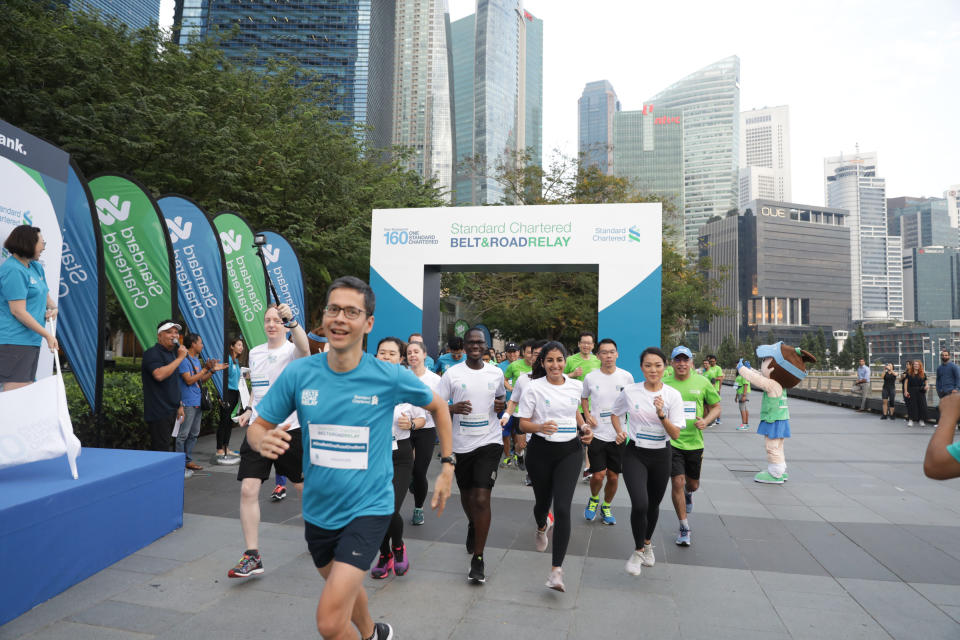 Standard Chartered Bank Singapore’s CEO Patrick Lee (in blue shirt) leading the 160-strong staff contingent in the 3.2km fun run around Marina Bay Promenade, as part of the bank’s Belt and Run Relay. The eight athletes chosen to run the relay are in white shirts, including Singapore’s Therese Neo (first from right). (PHOTO: Standard Chartered Singapore)