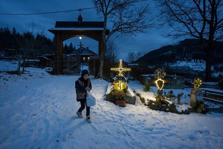 Un niño camina por un cementerio después de una misa por Navidad en Kryvorivnia, Ucrania, el 24 de diciembre de 2023.