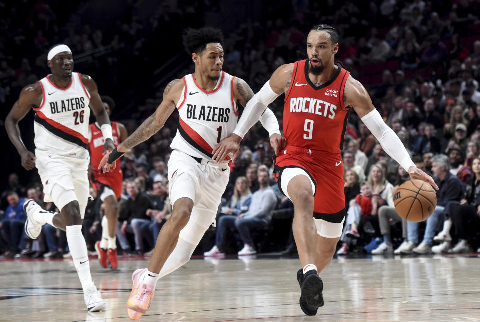Houston Rockets forward Dillon Brooks (9) dribbles the basketball against Portland Trail Blazers guard Anfernee Simons (1) as center Duop Reath (26) gives chase during the first half of an NBA basketball game in Portland, Ore., Friday, March 8, 2024. (AP Photo/Steve Dykes)