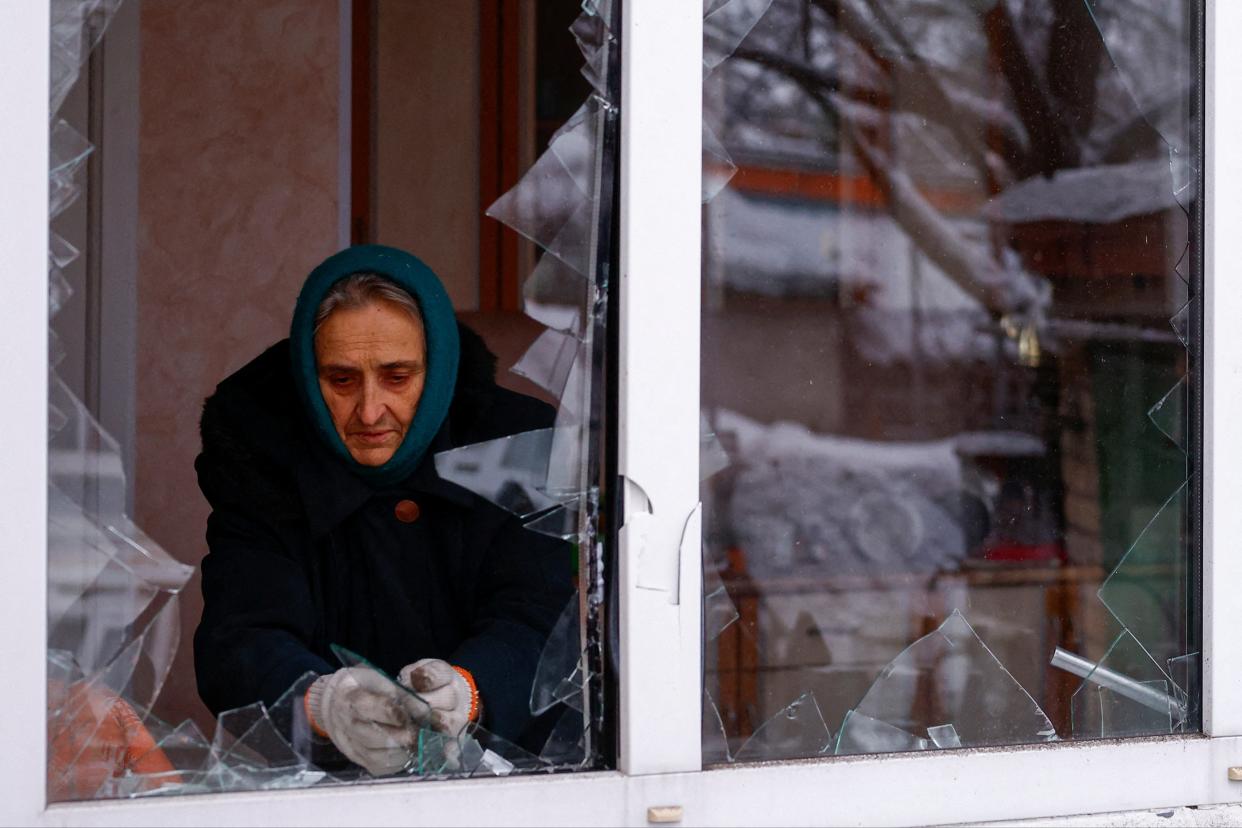 Local resident Nadiia Matviienko removes pieces of glass from a broken window of her house damaged by a Russian missile strike in Kyiv (REUTERS)