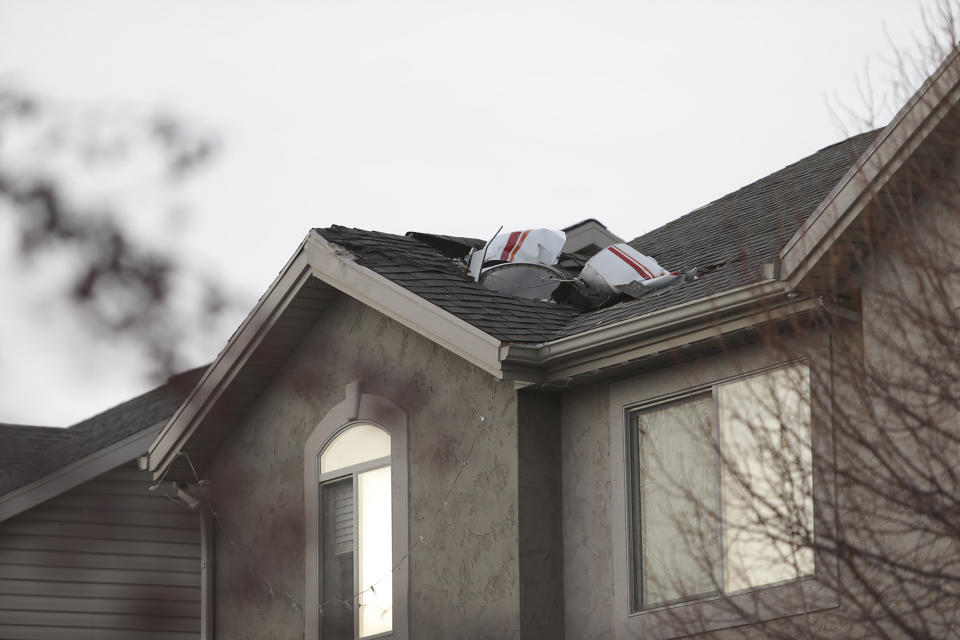 Debris from a small private plane that crashed in a residential area is shown on a roof Wednesday, Jan. 15, 2020, in Roy, Utah. The small plane crashed Wednesday, killing the pilot as the aircraft narrowly avoided hitting any townhomes, authorities said. (Ben Dorger/Standard-Examiner, via AP)