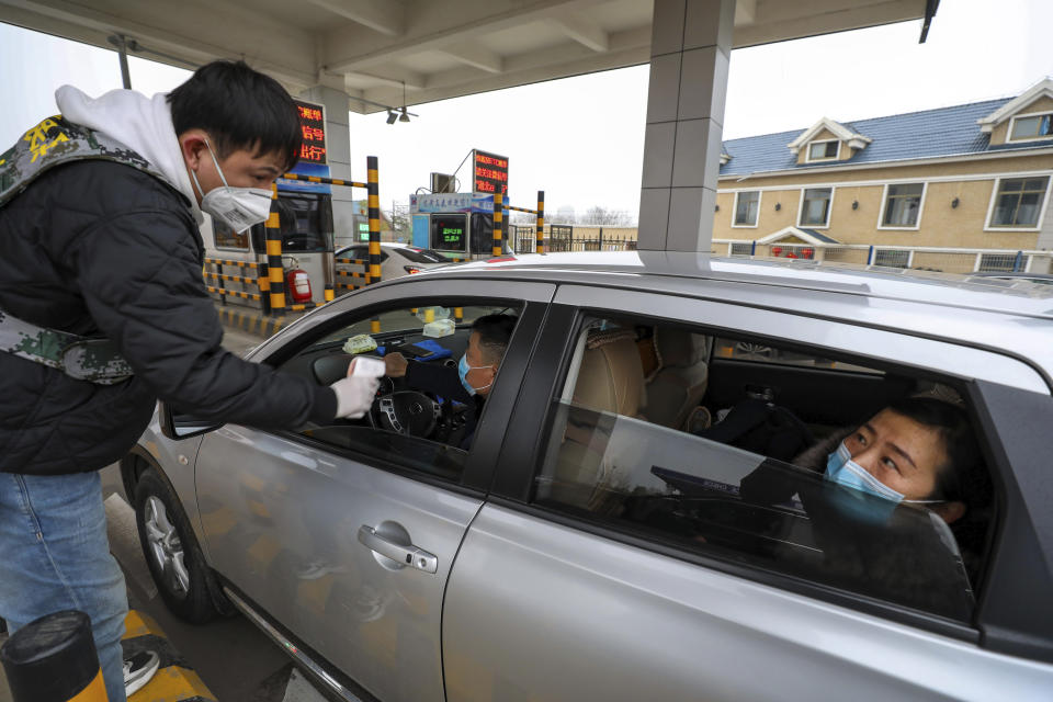 A militia member uses an thermometer gun to take a driver's temperature at a checkpoint at a highway toll gate in Wuhan in central China's Hubei Province, Thursday, Jan. 23, 2020. China closed off a city of more than 11 million people Thursday in an unprecedented effort to try to contain a deadly new viral illness that has sickened hundreds and spread to other cities and countries amid the Lunar New Year travel rush. (Chinatopix via AP)