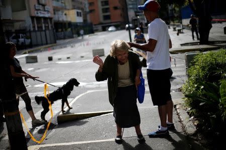 People cross under ropes used to close a sidewalk during a strike called to protest against Venezuelan President Nicolas Maduro's government in Caracas. REUTERS/Andres Martinez Casares