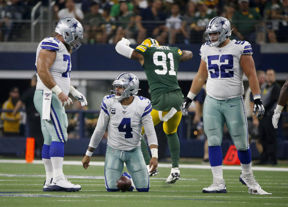 Dallas Cowboys' Travis Frederick, left, and Connor Williams (52) watch Dak Prescott (4) get up off the ground after being sacked by Green Bay Packers' Preston Smith (91) during the first half of an NFL football game in Arlington, Texas, Sunday, Oct. 6, 2019. (AP Photo/Ron Jenkins)