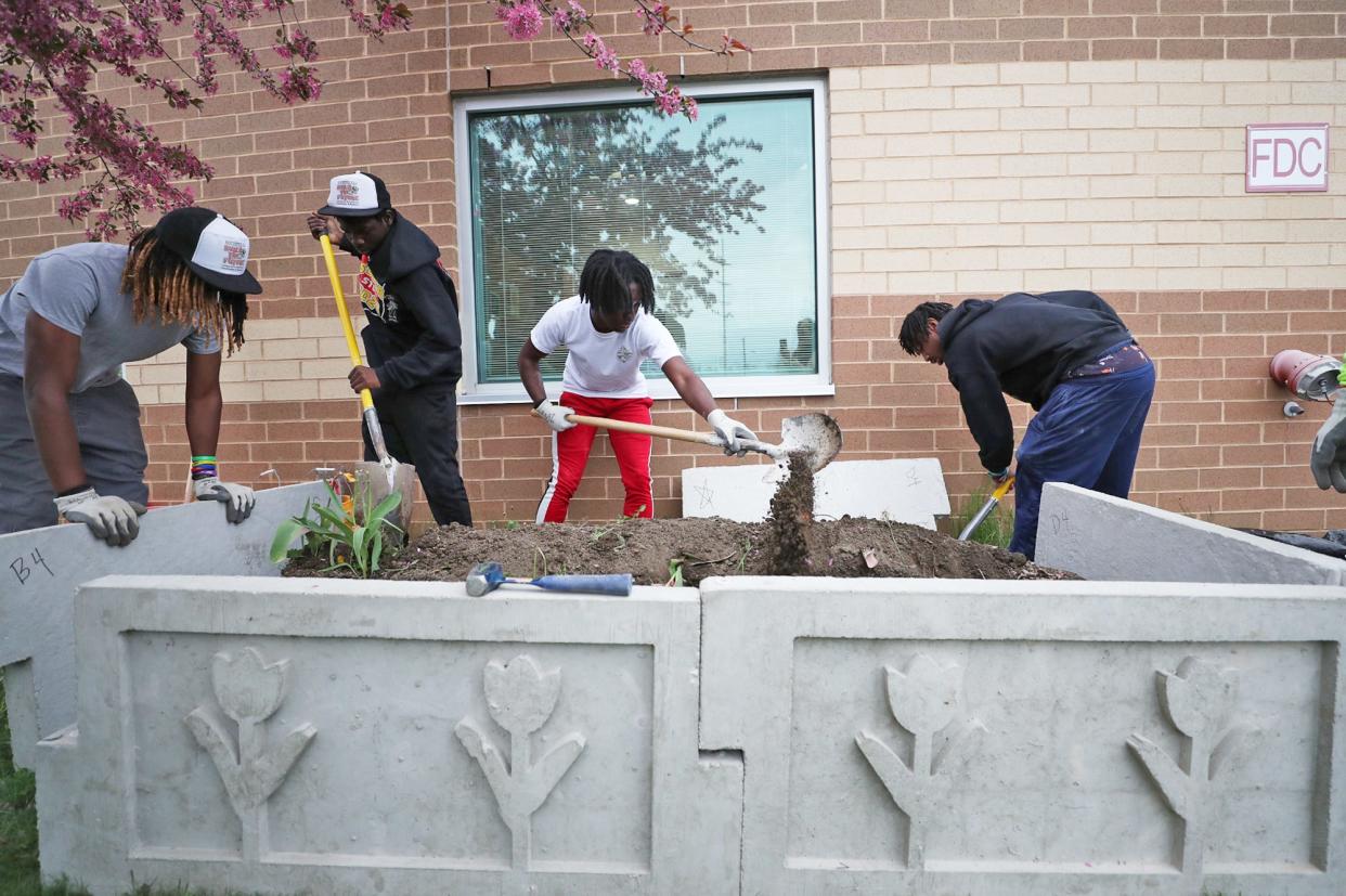 Buchtel CLC masonry students, from left, Jequelen Harrell, 18; Ryen Finney-Kimble, 18; Wylie Chears, 18; and Zyaire Lewis, 18, work together to install the the back two pieces of a planter at Helen Arnold CLC Wednesday.
