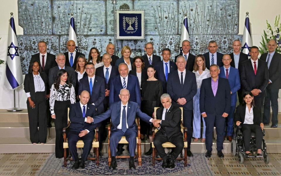 Israeli President Reuvin Rivlin (C) is flanked by Prime Minister Naftali Bennett (L) and alternate Prime Minister and Foreign Minister Yair Lapid (R) during a photo of the new coalition government - EMMANUEL DUNAND /AFP