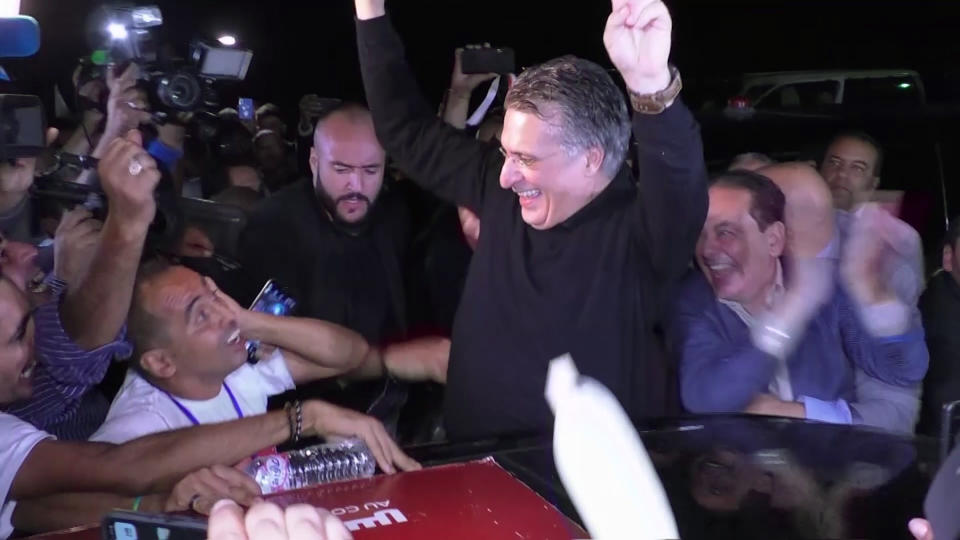 In this image from TV, Tunisian presidential candidate and media mogul Nabil Karoui, waves as he is greeted by jubilant crowds after he was released from prison in Mannouba, Tunisia, Wednesday Oct. 9, 2019, just four days before the upcoming presidential runoff election. Karoui has been jailed since August under investigation for alleged money laundering and tax fraud that he asserts as a politically motivated smear campaign. (AP Photo)