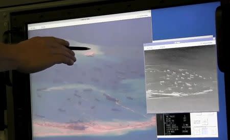 A U.S. Navy crewman aboard a P-8A Poseidon surveillance aircraft points to a computer screen purportedly showing Chinese construction on the reclaimed land of Fiery Cross Reef in the disputed Spratly Islands in this still image from video provided by the United States Navy May 21, 2015. REUTERS/U.S. Navy/Handout via Reuters ATTENTION EDITORS - THIS PICTURE WAS PROVIDED BY A THIRD PARTY. REUTERS IS UNABLE TO INDEPENDENTLY VERIFY THE AUTHENTICITY, CONTENT, LOCATION OR DATE OF THIS IMAGE. THIS PICTURE WAS PROCESSED BY REUTERS TO ENHANCE QUALITY. EDITORIAL USE ONLY. NOT FOR SALE FOR MARKETING OR ADVERTISING CAMPAIGNS.