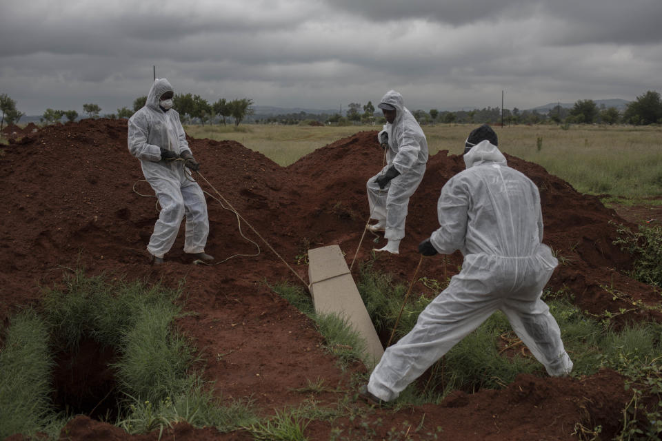 In this Thursday, April 12, 2018, photo mortuary workers bury the coffin of an unidentified male in a "pauper grave" at a Olifantsvlei cemetery outside Johannesburg. At least five are placed on top of each other in each grave. (AP Photo/Bram Janssen)