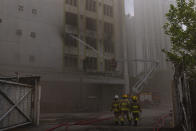 Firefighters battle a fire in Cheung Sha Wan, a residential and industrial area, in Hong Kong, Friday, March 24, 2023. Hong Kong firefighters were battling a blaze Friday at a warehouse that forced more than 3,000 people to evacuate, including students, police said. (AP Photo/Louise Delmotte)