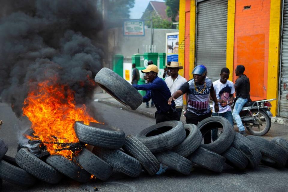 Protesters throw wheels onto a burning barricade during a demonstration demanding the resignation of President Jovenel Moïse, in Port-au-Prince, Haiti, Friday, Jan. 15, 2021.