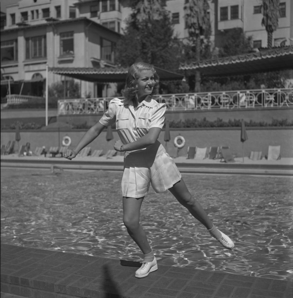 Turner standing in a pose by a swimming pool wearing an all-white outfit in 1940.