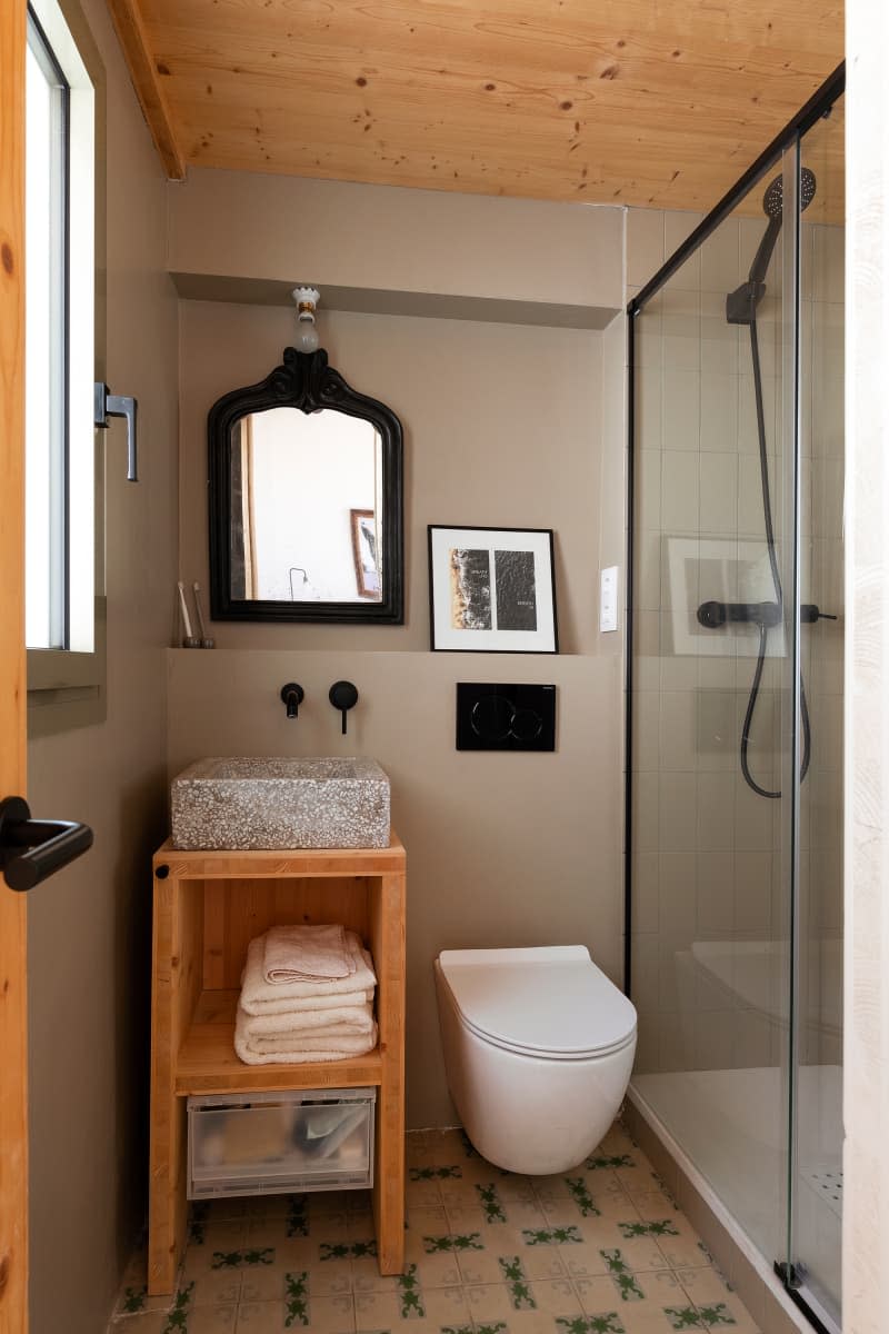 gray bathroom with wood ceiling, wood shelves, and black accents