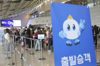 Passengers wearing face masks to help protect against the spread of the coronavirus line up to board planes ahead of the upcoming Chuseok holiday, the Korean version of Thanksgiving Day, at the domestic flight terminal of Gimpo airport in Seoul, South Korea, Wednesday, Sept. 30, 2020. The signs read: "Departure passenger." (AP Photo/Ahn Young-joon)