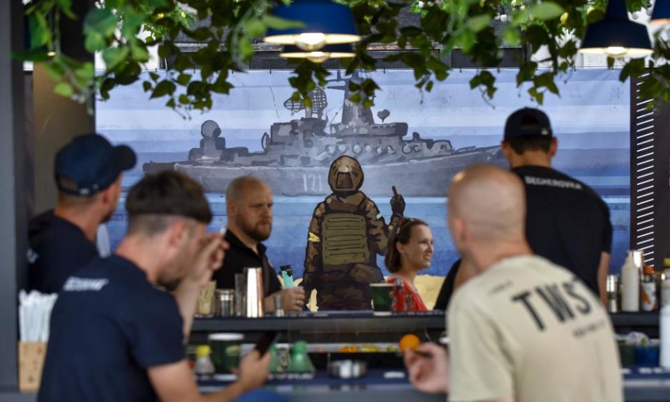 Poster in bar on warship and soldier with drinkers in foreground