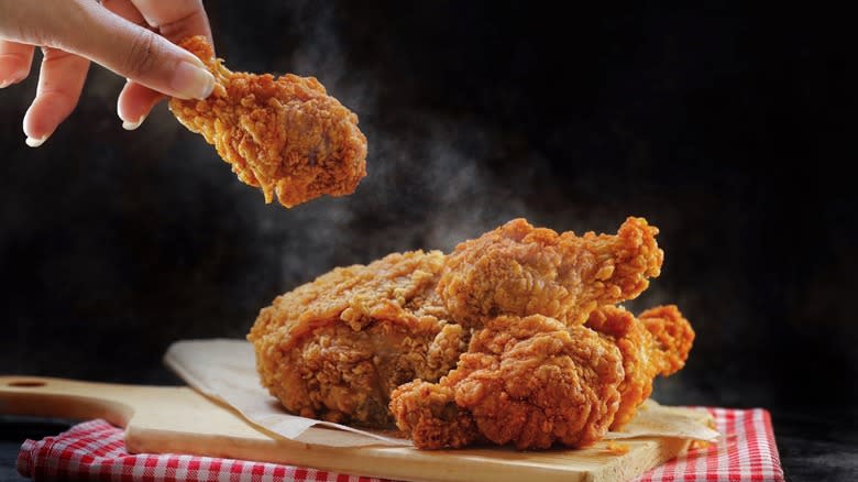 Hand holding steaming fried chicken 