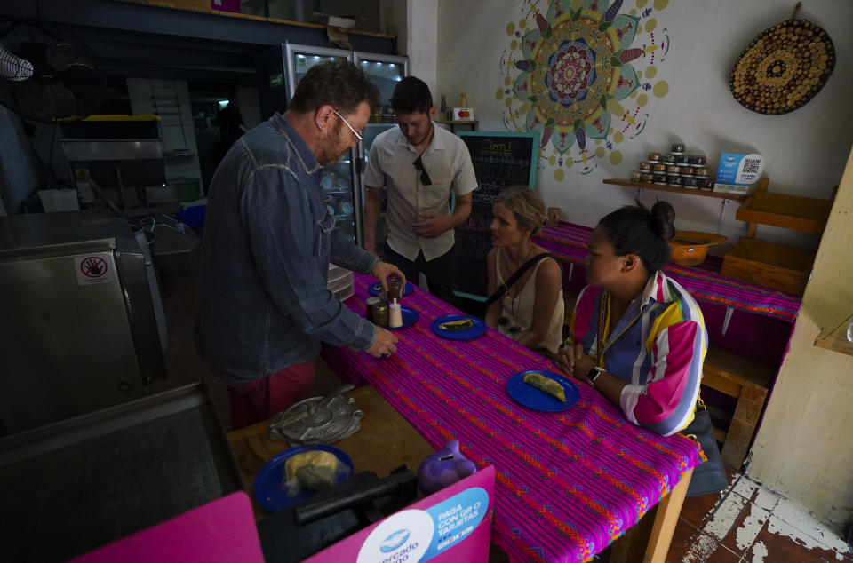Turistas se preparan para probar tortillas fabricadas con maíz nativo en una "tortillería" en el vecindario de Condesa, en Ciudad de México, el miércoles 24 de mayo de 2023. (AP Foto/Fernando Llano)