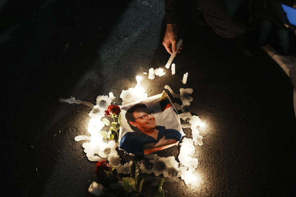 A supporter lights a candle around a photo of slain candidate Fernando Villavicencio during an open-air Mass prior to the closing campaign rally of the "Movement Construye" party in Quito, Ecuador, Thursday, Aug. 17, 2023. The upcoming snap election set for Aug. 20 was called after President Guillermo Lasso dissolved the National Assembly by decree in May, to avoid being impeached. (AP Photo/Dolores Ochoa)