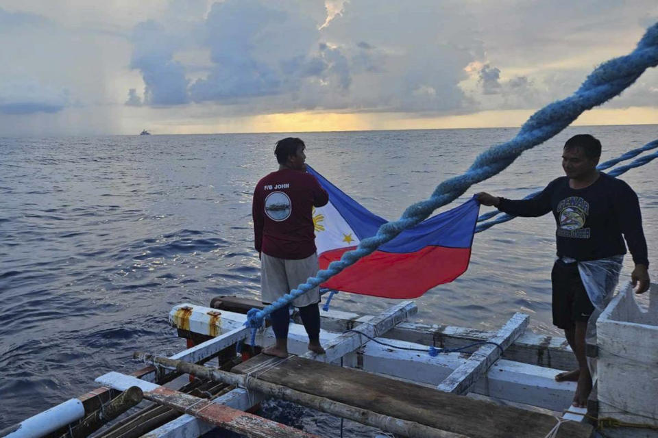In this photo provided by Atin-Ito/Akbayan Party, fishermen raise a Philippine flag on their boat as activists and volunteers from a nongovernment coalition called Atin Ito, Tagalog for This is Ours, sailed at the South China Sea on Thursday May 16, 2024. About 100 Filipino activists on wooden boats have decided not to sail closer to a fiercely disputed shoal in the South China Sea on Thursday to avoid a confrontation with dozens of Chinese coast guard and suspected militia ships guarding the area. (Atin-Ito/Akbayan Party via AP)