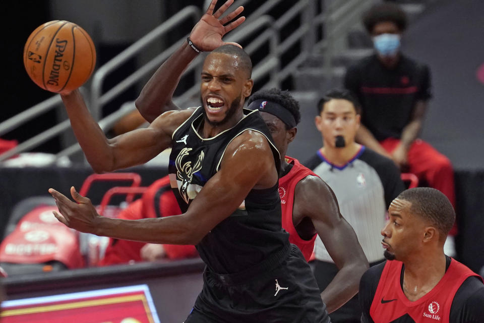 Milwaukee Bucks forward Khris Middleton (22) passes the ball in front of Toronto Raptors forward Pascal Siakam (43) and guard Norman Powell (24) during the first half of an NBA basketball game Wednesday, Jan. 27, 2021, in Tampa, Fla. (AP Photo/Chris O'Meara)