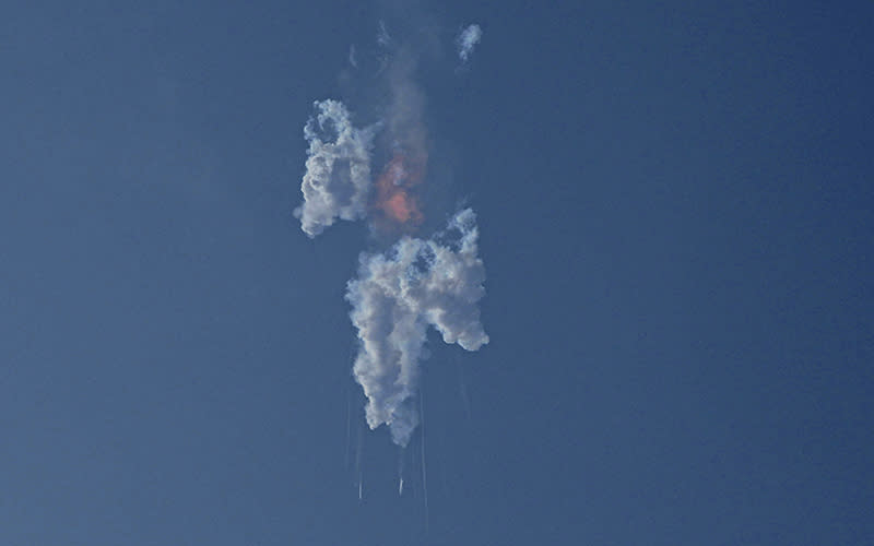 A cloud of smoke and trails of falling debris are seen after SpaceX's Starship exploded minutes after blasting off