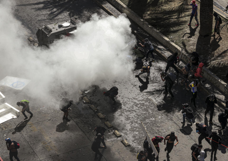 A police armored vehicle sprays tear gar against anti-government demonstrators during a protest in Santiago, Chile, Tuesday, Oct. 22, 2019. Chile has been facing days of unrest, triggered by a relatively minor increase in subway fares. The protests have shaken a nation noted for economic stability over the past decades, which has seen steadily declining poverty despite persistent high rates of inequality. (AP Photo/Esteban Felix)