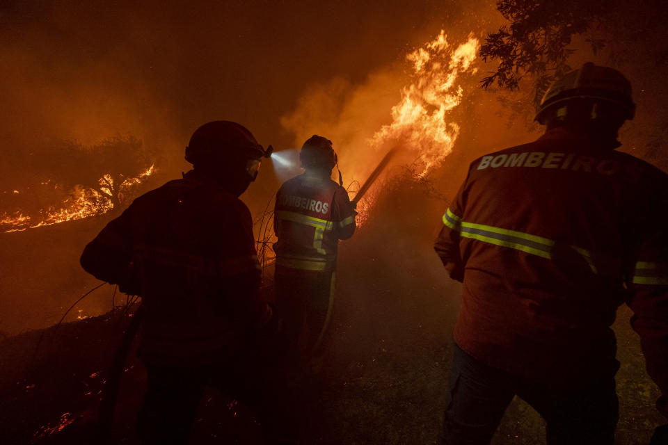 Fighters try to extinguish a wildfire near Cardigos village, in central Portugal on Sunday, July 21, 2019. About 1,800 firefighters were struggling to contain wildfires in central Portugal that have already injured 20 people, including eight firefighters, authorities said Sunday. (AP Photo/Sergio Azenha)