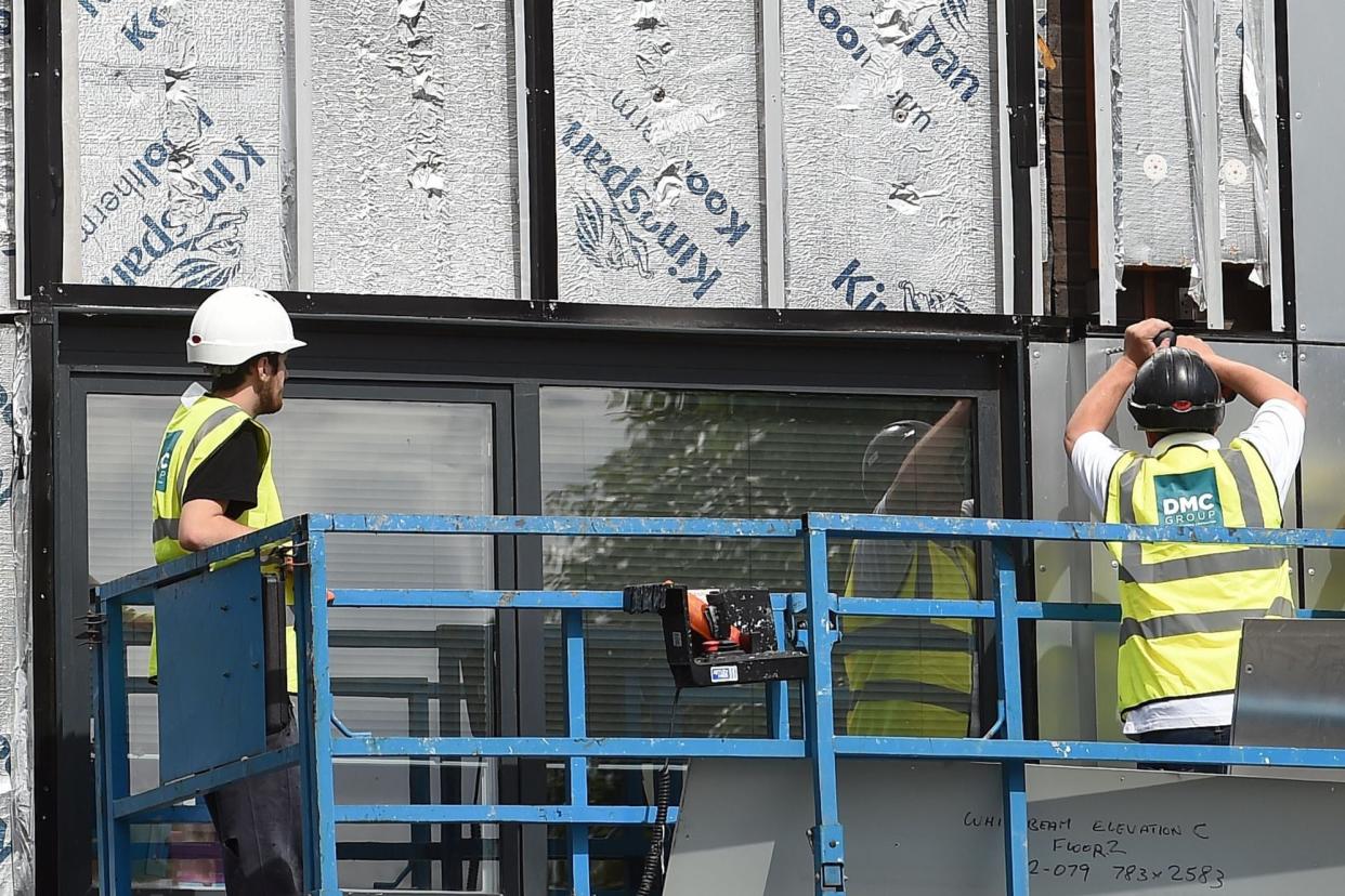 <p>Workers remove cladding from a tower block</p> (AFP via Getty Images)