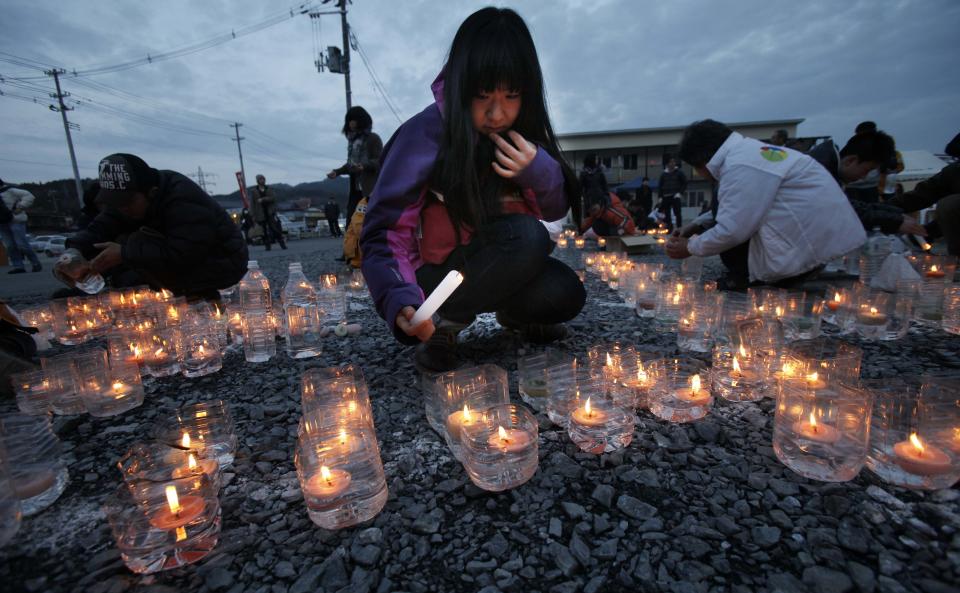 A girl lights candles in front of a temporary shopping complex in the earthquake and tsunami-devastated city of Kesennuma, Iwate prefecture, northeastern Japan, Sunday, March 11 2012, to mark the first anniversary of the massive disaster that devastated Japan's northeast one year ago. (AP Photo/Koji Sasahara)