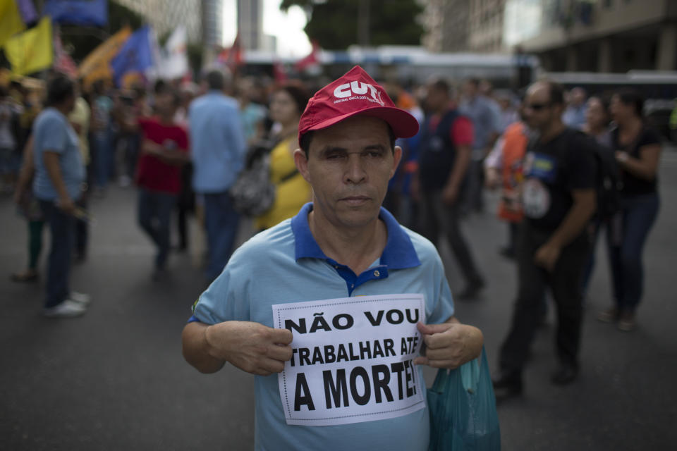 A demonstrator holds a sign that reads in Portuguese "I will not work until I die" during a protest against federal government proposed reforms in Rio de Janeiro, Brazil, Wednesday, March 15, 2017. People protested across the country against proposed changes to work rules and pensions. (AP Photo/Leo Correa)