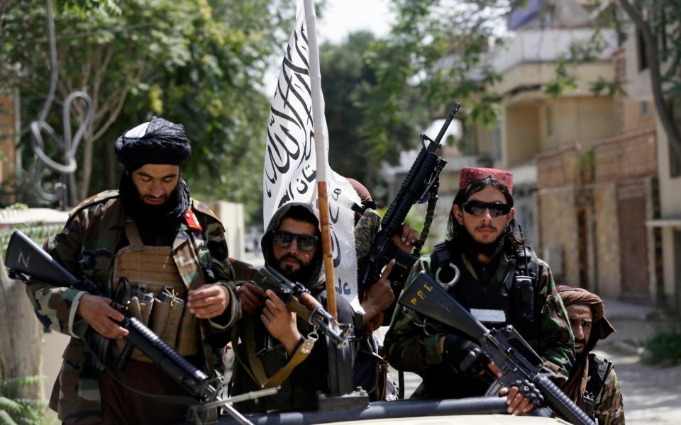 Taliban fighters in Kabul, bearing the country's new flag - AP Photo/Rahmat Gul, File