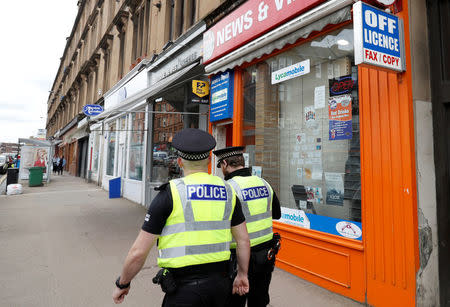 Police officers walk past a shop with a license to sell alcoholic beverages in Glasgow, Scotland, Britain, May 1, 2018. REUTERS/Russell Cheyne