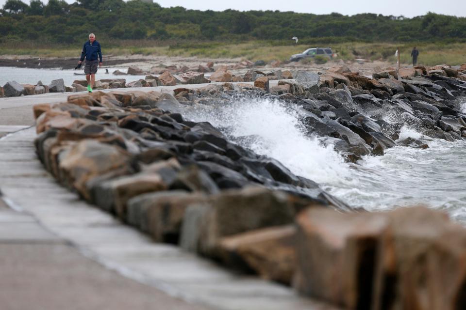 A man walks across as waves generated by Hurricane Lee crash onto the Gooseberry Island causeway in Westport.